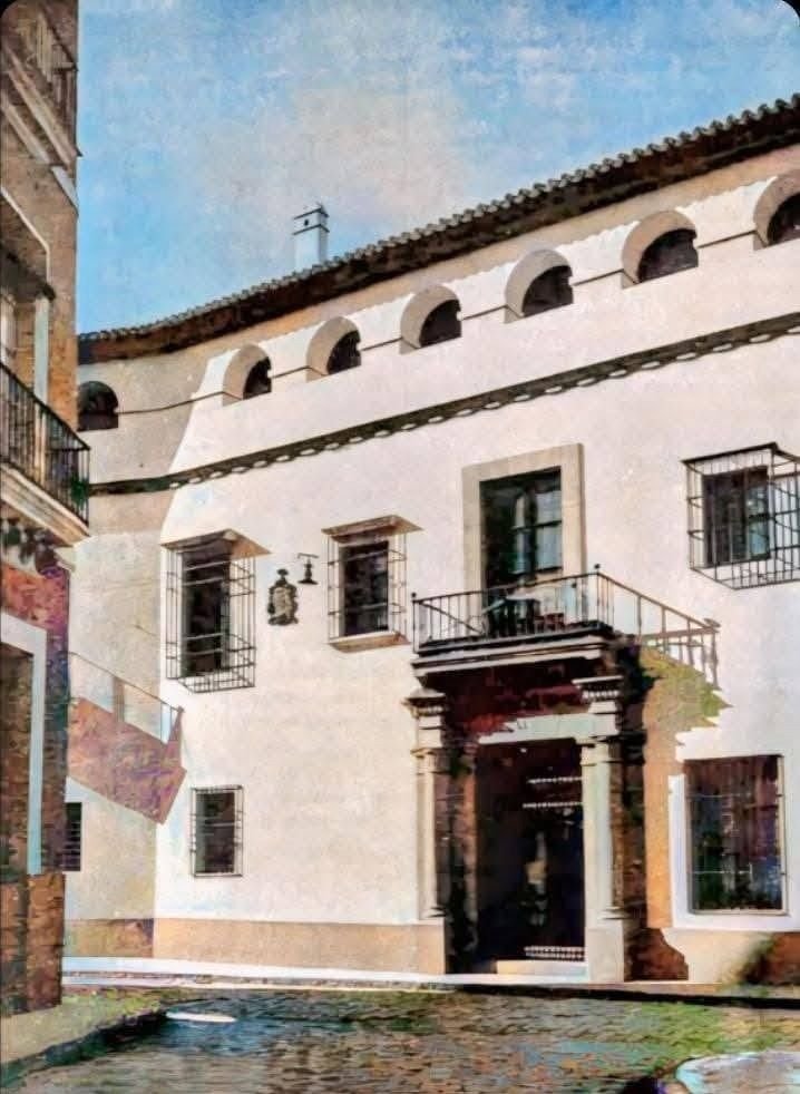 Casa encalada de dos plantas con balcón y portada, en una calle empedrada
