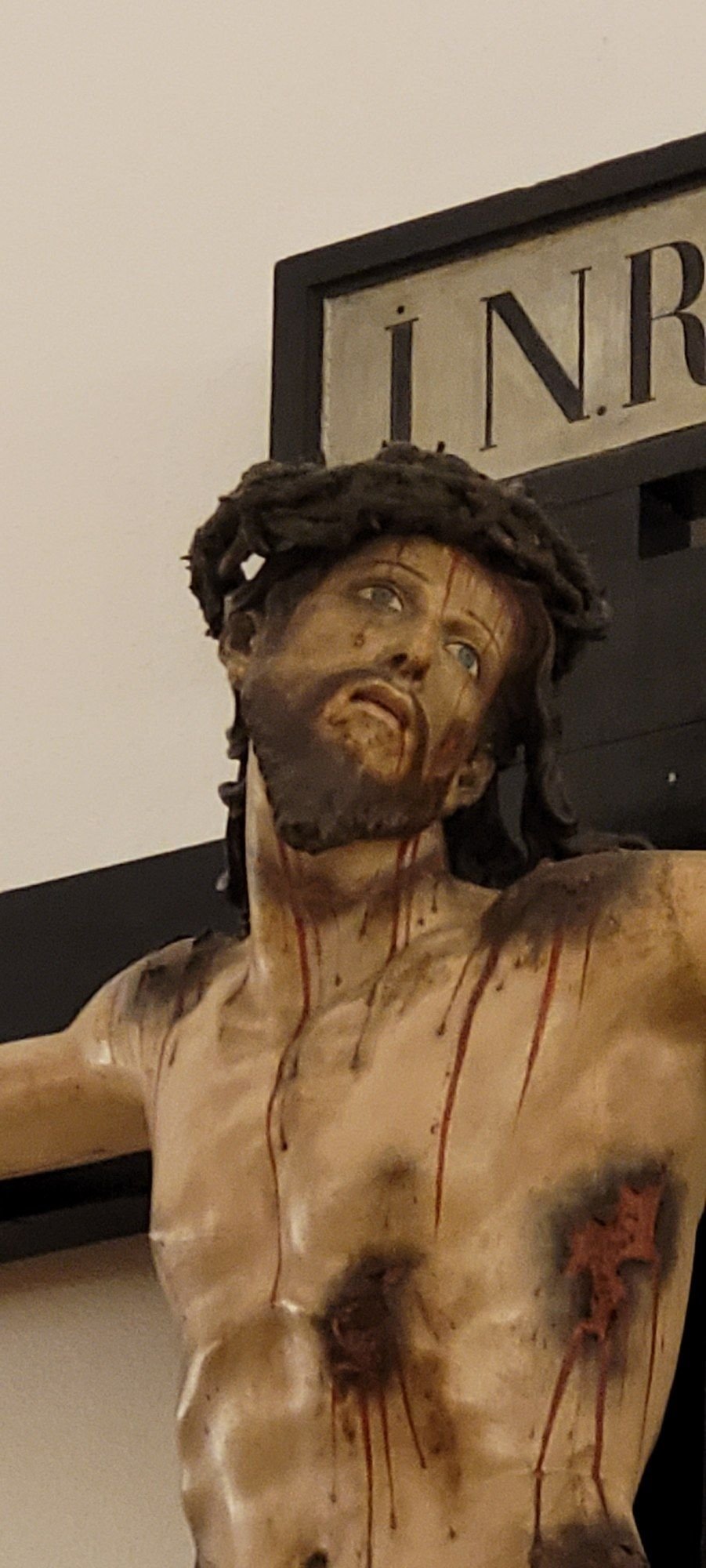 Detalle del Cristo crucificado de madera policromada, con la corona de espinas y la cartela INRI