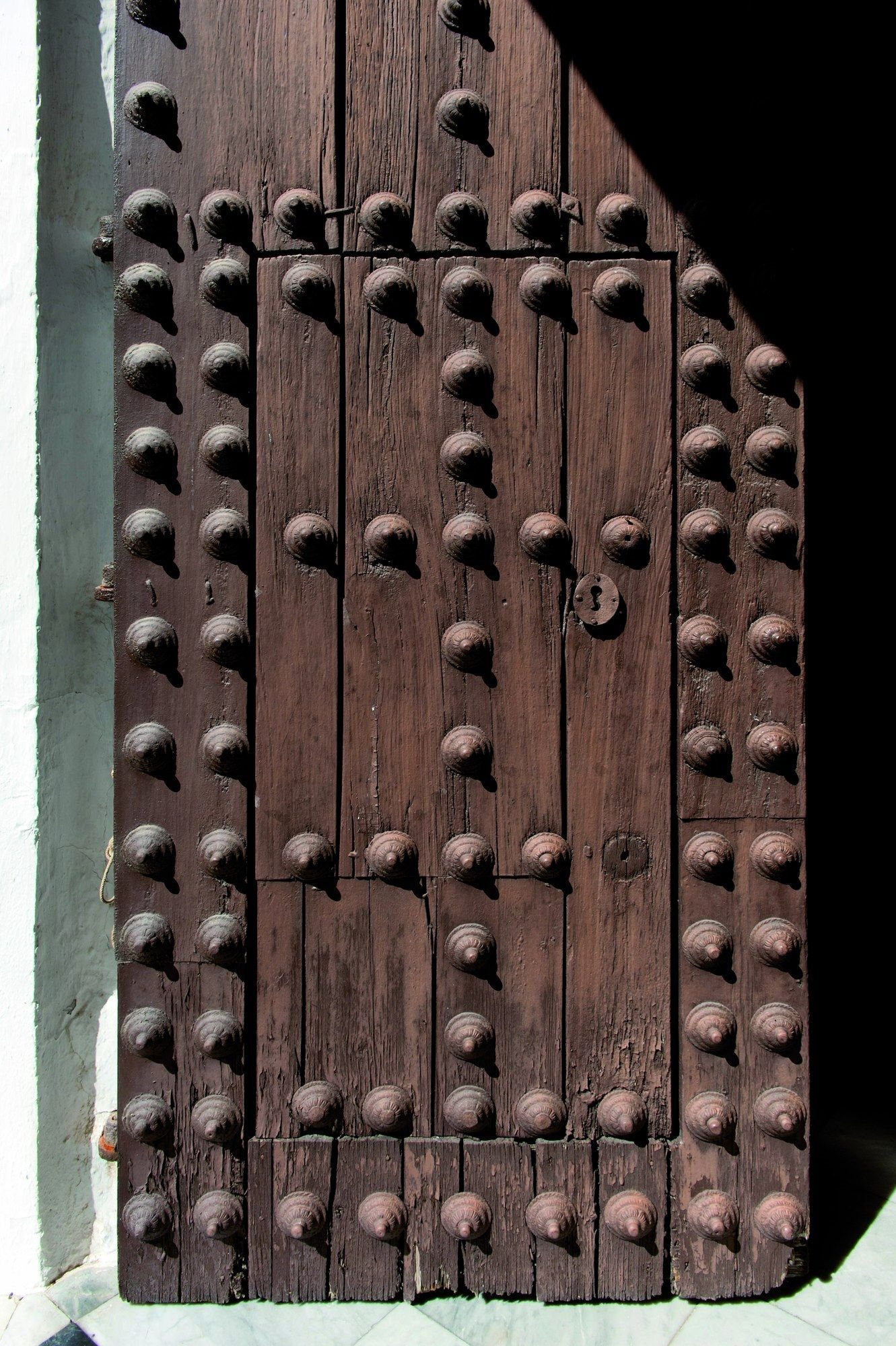 Portón de madera con clavos de hierro, entreabierto